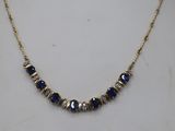 a gold necklace with blue and white beads on a gold chain