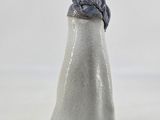 a white vase with a blue top on a white table