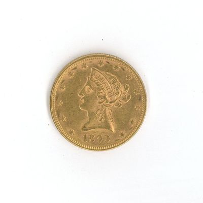 une pièce d'or posée sur un fond blanc, sur laquelle figure la tête d'une femme