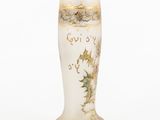 a white vase with gold decoration on it on a white surface