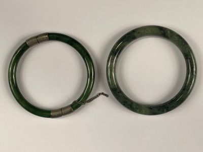 Deux bracelets joncs en jade dont un ouvrant dont le fermoir…