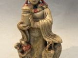 statue d'une femme assise sur un rocher, avec un oiseau sur l'épaule