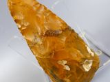 an orange piece of rock sitting on top of a clear glass holder