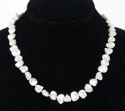 un collier de perles blanches autour du cou d'un mannequin noir
