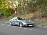a silver sports car driving down the road in the woods