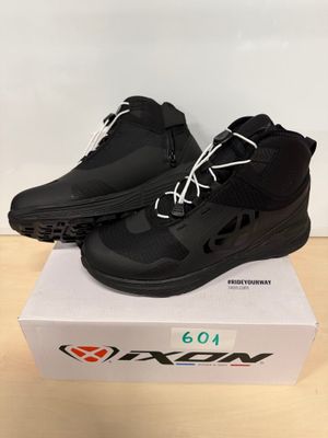 une paire de chaussures noires posée sur une boîte, elle-même posée sur une table