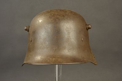 an old helmet on a metal stand on a gray background