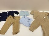 four pairs of baby clothes are laid out on a table