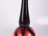 un vase rouge et jaune posé sur une surface blanche