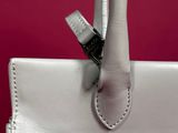 a close up of a white handbag with a metal handle