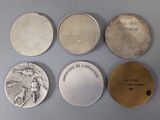 four different types of silver coins on a gray surface