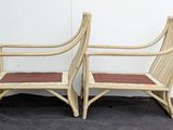 pair of bamboo chairs with red cushions on a black surface