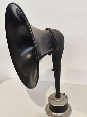une enceinte noire à l'ancienne posée sur une table blanche, avec un fond blanc