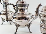 a silver tea set on a table with silverware on it