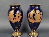 pair of blue and gold vases with figures on them on a gray background