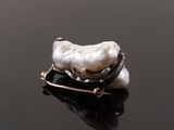 a close up of a broochle with a white pearl on a black surface