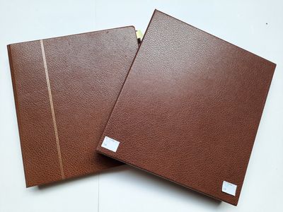 une paire de classeurs en cuir marron posés sur une surface blanche