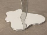 a glass table with a silver base and a flower on it