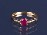 gros plan d'une bague en or avec un rubis et des diamants