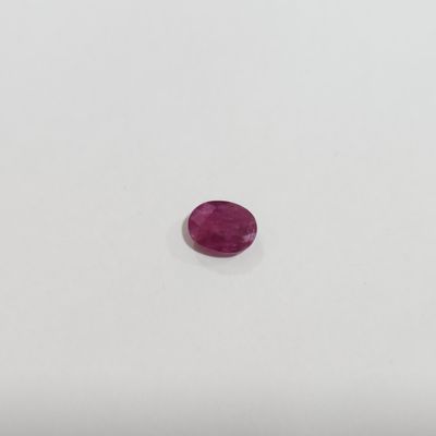 a pink oval shaped ruby stone on a white surface