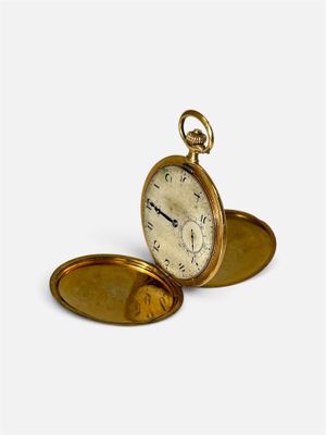 une montre de poche en or posée sur une surface blanche