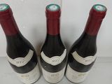 three bottles of red wine are lined up on a white surface