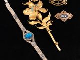 a close up of a bracelet, brooch, and other jewelry on a black surface
