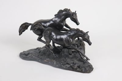 statue of two horses running on a rock on a white background