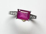 un gros plan d'une bague en pierre rose et diamants posée sur une surface blanche