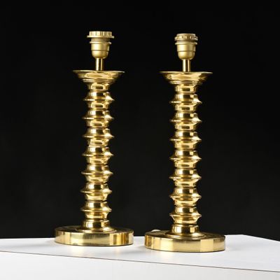 une paire de bougeoirs en laiton posés sur une table blanche