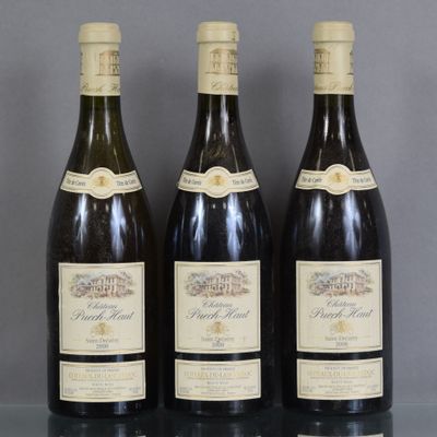Trois bouteilles de vin sont alignées sur une table en verre