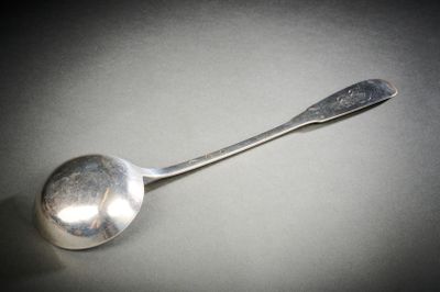 une cuillère en argent avec un manche de cuillère sur une table
