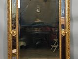 un grand miroir avec un cadre doré accroché au mur
