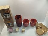 a box of candles, a candle holder, a candle and a cup on a table