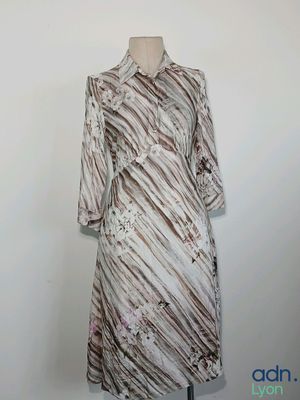 La robe est posée sur un mannequin adossé à un mur blanc.