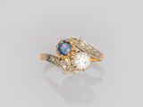 gros plan d'une bague en or avec un saphir et des diamants