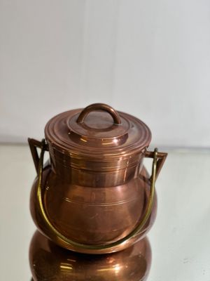 a small copper pot sitting on top of a glass table