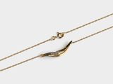 un collier plaqué or composé d'une longue chaîne sur laquelle est accroché un oiseau