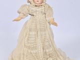 a close up of a doll wearing a white dress and bonnet