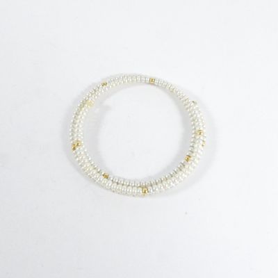 un bracelet blanc orné de perles avec des touches dorées sur fond blanc