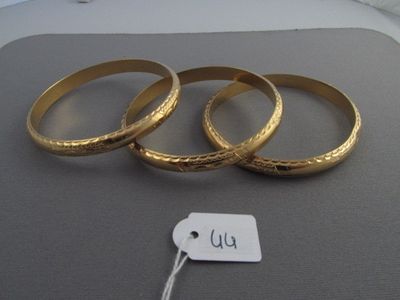 trois bagues en or, accompagnées de leur étiquette de prix, sont posées sur une table