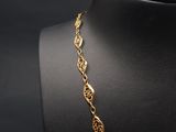 a gold plated necklace on a mannequin with a black background