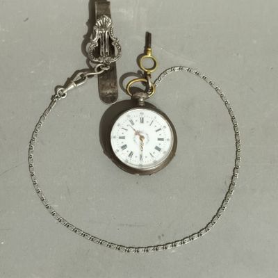 a silver pocket watch on a chain with a chain around it