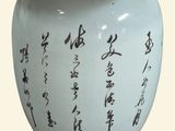 a white vase with writing on it on a wooden stand