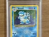 une carte Pokémon dans un étui en plastique transparent posé sur une table en bois