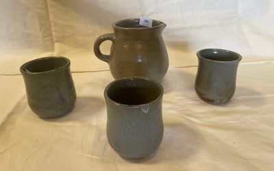 three cups and a jug sitting on a table