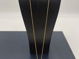 a gold plated necklace with a clear glass pendant on a mannequin