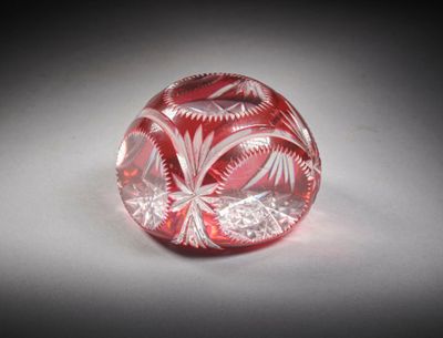 une image représentant un objet en verre rouge et blanc posé sur une surface blanche