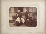 une vieille photo d'une famille posant devant une maison