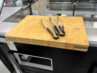 une planche à découper sur laquelle sont posés des couteaux, dans une cuisine